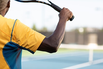 Man with elbow pain swinging tennis racket